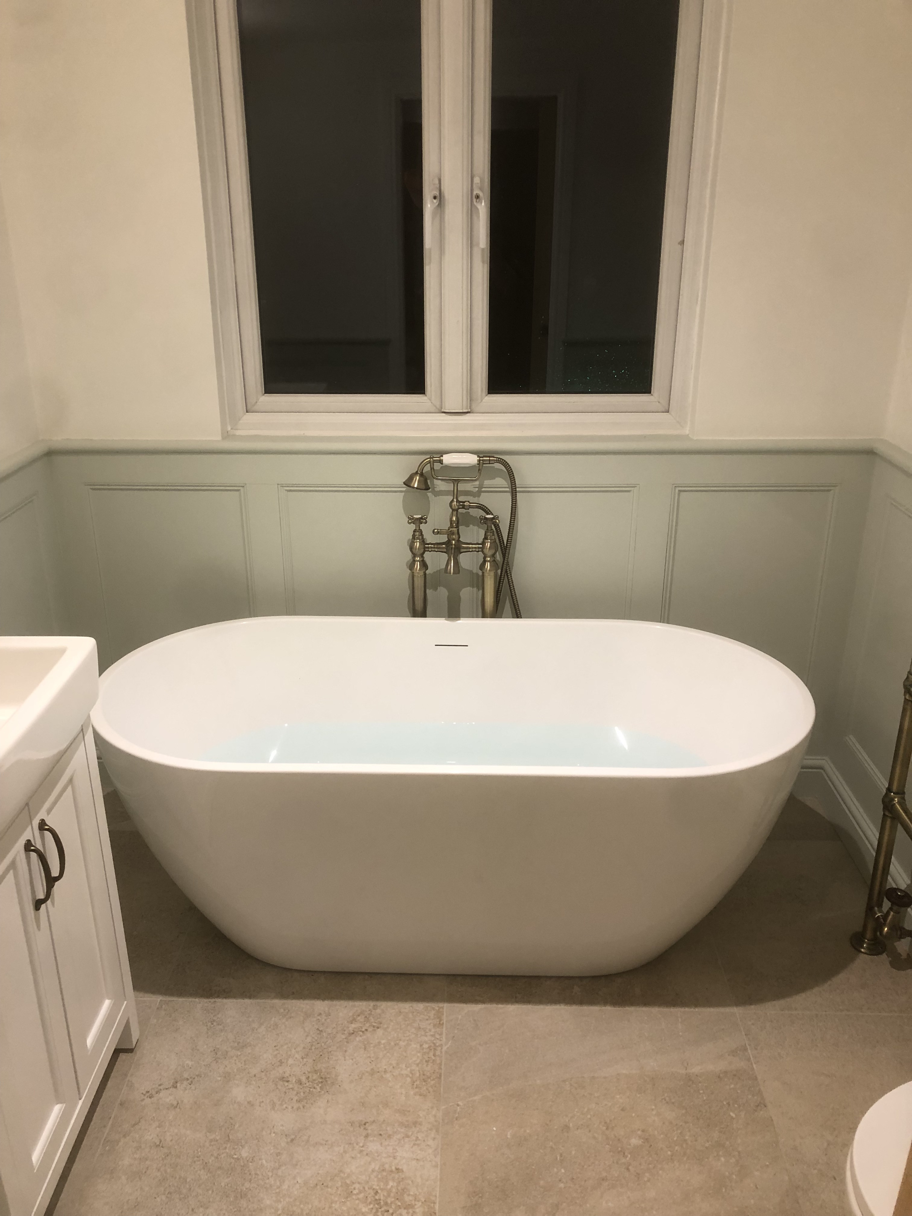 Freestanding bath with brass fittings and sage panelling