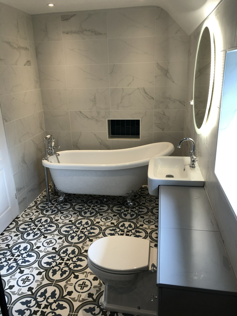 Clawfoot bath with marble wall tiles and patterned floor